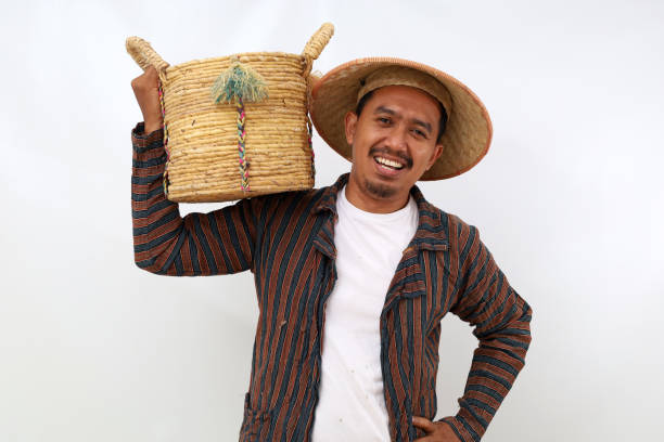istock Happy asian farmer standing while holding a basket on his shoulder. Isolated on white background 1444795620
