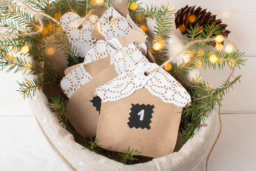 Christmas DIY with your own hands.Advent calendar made of kraft paper using openwork napkins with eco basket with bokeh. Flat lying