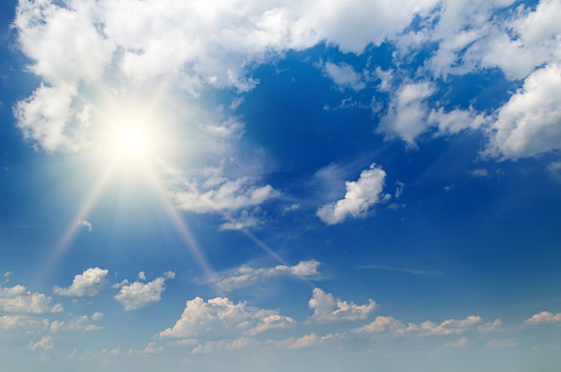 cloudscape image of shinning sun over blue sky and clouds
