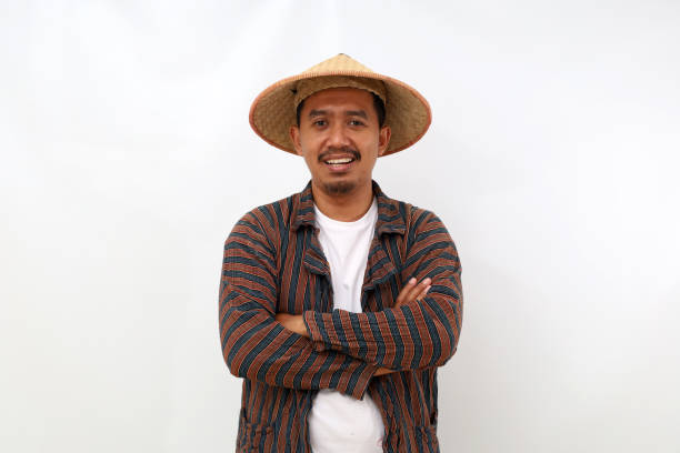 istock Happy asian farmer standing with a hat and folded hands while looking at the camera. Isolated on white background 1444800224
