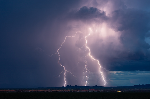 Bright lightning bolt strikes and dark storm clouds from a monsoon thunderstorm near Tucson, Arizona.