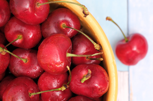 Bowl of red cherries isolated on weathered wooden background.