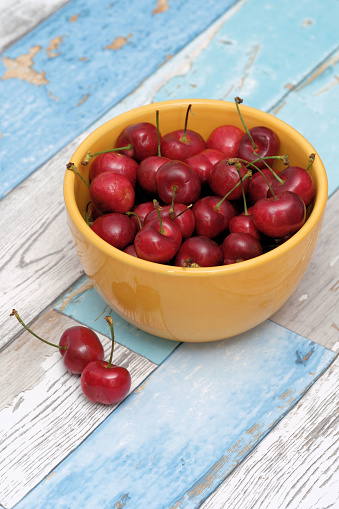 Bowl of red cherries isolated on weathered wooden background.