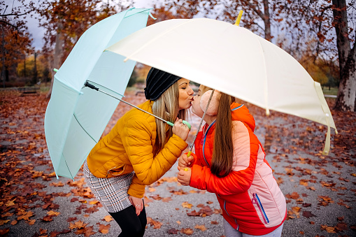 Kiss of mother and daughter on a rainy autumn day