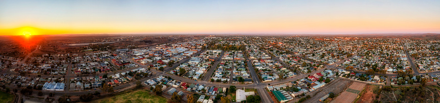 Wide aerial sunrise panorama over Broken hill city from sun horizon to outskirt suburbs with downtown and open pit mine.