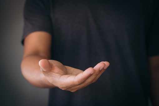 The man is standing and shows an outstretched hand with an open palm. Businessman showing empty hand and presenting with hand empty copy space. Open hand, Holding, giving, showing, presenting concept.