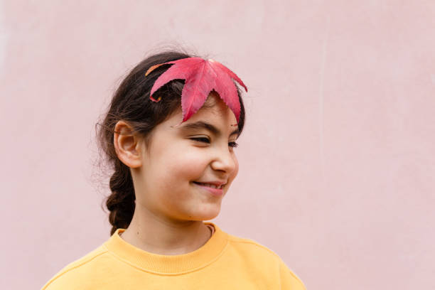 smiling girl with big red leaf in her hair
