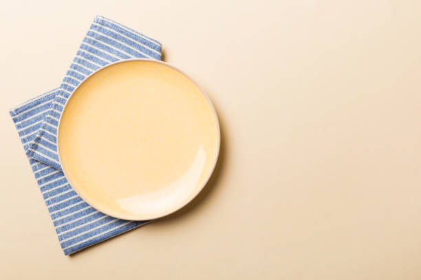 istock Top view on colored background empty round yellow plate on tablecloth for food. Empty dish on napkin with space for your design 1444825909
