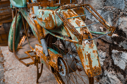 Una vieja motocicleta oxidada de color turquesa se encuentra desmontada contra el fondo de una escalera de piedra. Primer plano de los detalles oxidados de un viejo vehículo de dos ruedas. photo