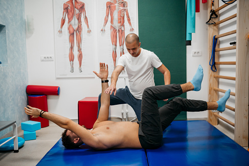 Physiotherapist helping a patient while doing his exercises