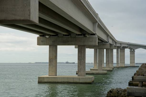 istock Pylon supporting transition spans joining box girder bridge over Oregon Inlet with distant freighter 1444827675