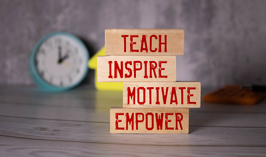 Teach inspire motivate empower, text words on wooden blocks.