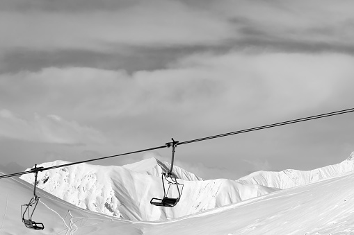 Chair lift at ski resort. Caucasus Mountains, Georgia, region Gudauri. Snowy high mountains in winter. Black and white toned image.