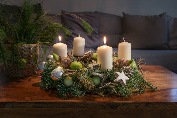 istock Second Advent, wreath with two burning white candles and Christmas decoration on a wooden table in front of the couch, festive home decor, copy space, selected focus 1444836794
