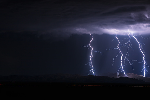 Dramatic thunderstorm lightning bolts in the night sky with copy space. Extreme weather concept or background.