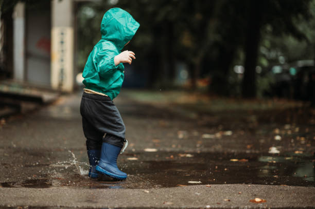 istock Happy boy playing outside on a rainy day wearing rubber boots and jacket 1444840145
