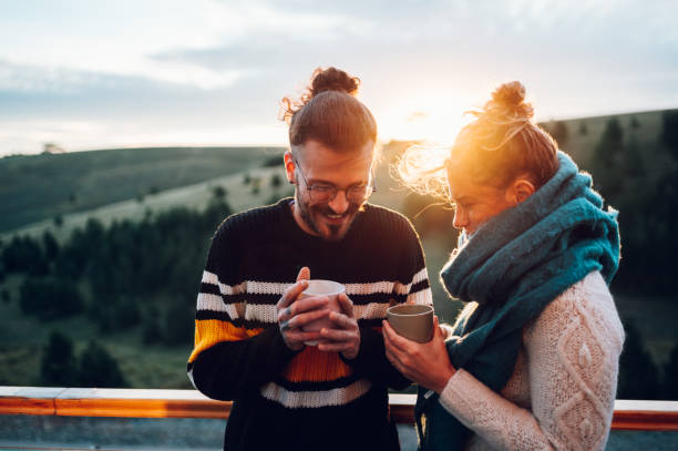 istock Young couple drinking coffee or tea while standing on their balcony at sunrise 1444840176