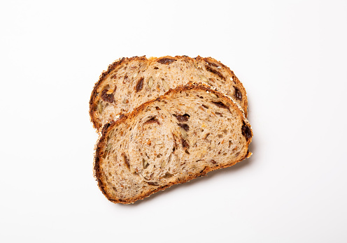 Slices of wholegrain bread with seeds on a dark wooden background. Selective focus.