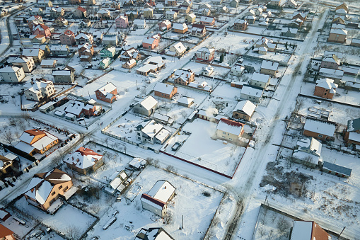 Aerial view of private homes with snow covered roofs in rural suburbs town area in cold winter.