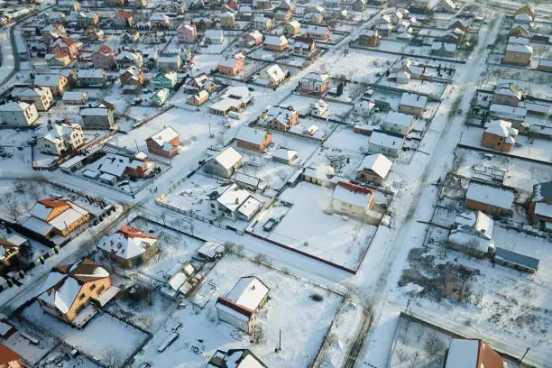 Photo of Aerial view of private homes with snow covered roofs in rural suburbs town area in cold winter