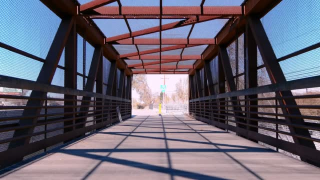 Riding across a Metal covered girder pedestrian bridge with diminishing perspective