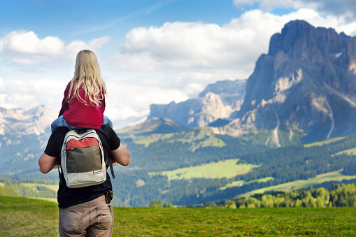 Father and his daughter admiring a view of Seiser Alm, the largest high altitude Alpine meadow in Europe, with stunning rocky mountains on the background. South Tyrol province of Italy, Dolomites.