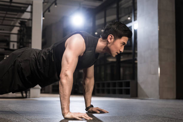 A young male athlete doing push-ups in the gym Suitable for fitness, sports, gym, fitness trainer, fitness place, sportswear, sports equipment, physical exercise, health, sports drink, protein powder, vitamin print advertising. sportsman professional sport side view horizontal stock pictures, royalty-free photos & images