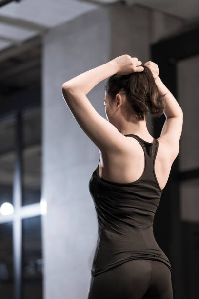A young sports woman tying her hair in the gym Suitable for fitness, sports, gym, fitness trainer, fitness place, sportswear, sports equipment, physical exercise, health, sports drink, protein powder, vitamin print advertising. woman tying hair in ponytail getting ready for exercising stock pictures, royalty-free photos & images