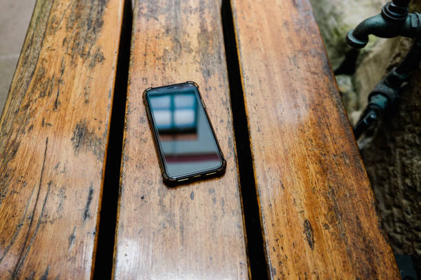 A black phone laying on an old scratched tabletop.