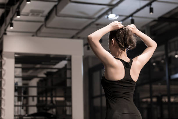 A young sports woman tying her hair in the gym Suitable for fitness, sports, gym, fitness trainer, fitness place, sportswear, sports equipment, physical exercise, health, sports drink, protein powder, vitamin print advertising. woman tying hair in ponytail getting ready for exercising stock pictures, royalty-free photos & images