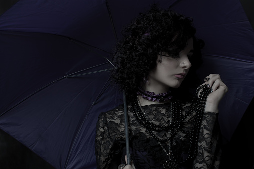 Old fashioned lady with umbrella over dark background