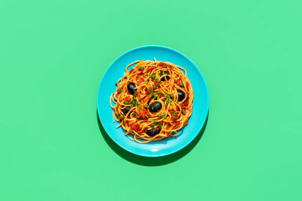 istock Spaghetti puttanesca plate, above view on a green background 1444871102