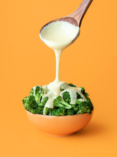 Brocolli with cheddar cheese dish. Pouring melted cheese over cooked broccoli.