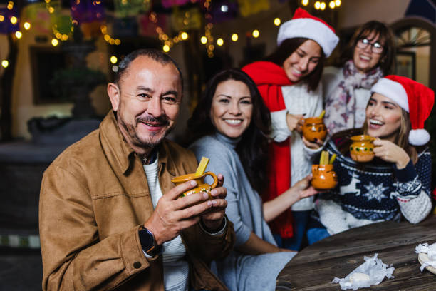 ritratto dell'uomo anziano ispanico che tiene una tazza di punch alla frutta alla tradizionale festa di posada per natale in messico america latina - pinata mexico christmas mexican culture foto e immagini stock