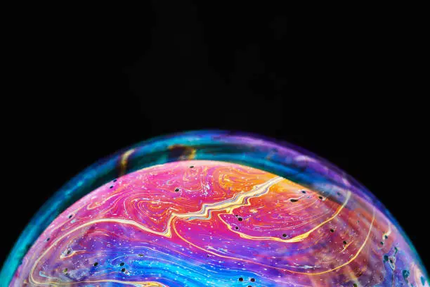 Photo of Virtual reality space with abstract multicolor psychedelic planet. Closeup Soap bubble like an alien planet on black background