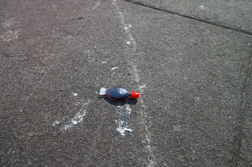 Tube of soy sauce on asphalt in the afternoon sun.