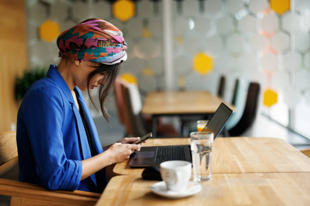 istock Businesswoman using phone while working on a laptop in restaurant 1444898945