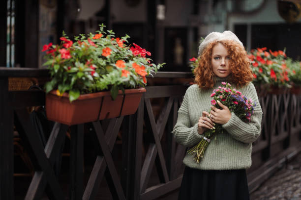 Woman portrait in a beret sweater holding a bouquet of flowers of the restaurant background stock photo