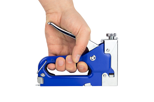 construction stapler in a male hand, isolated from the background, repair and construction tool