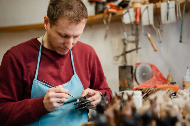 istock Carpenter painting wooden figurines in his workshop 1444911217