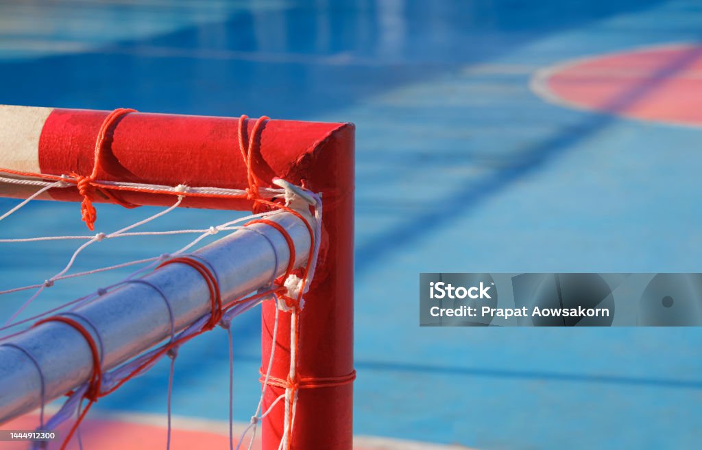 Focus at top right corner of red and white soccer goal crossbar with blurred background of outdoor futsal court Concrete Stock Photo