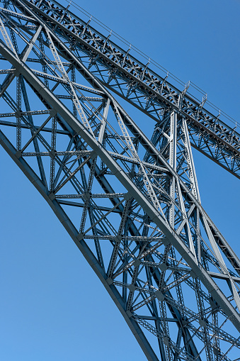 Close-up detail of the iron structure of Ponte de Dom Luis I, iconic double-deck metal arch bridge spanning over Douro River and connecting Ribeira and Vila Nova de Gaia neighborhoods, Porto, Portugal.