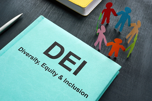 A Book about DEI diversity, equity and inclusion and paper figurines.