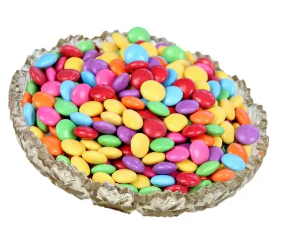 Chocolate buttons in colors of rainbow.  Delicious candies on white.
