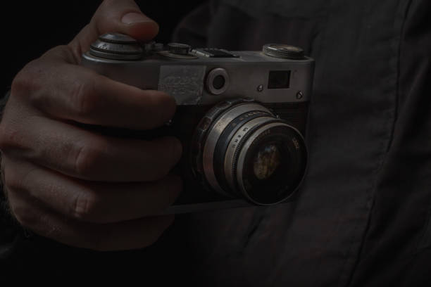 istock man holding Retro film photo camera isolated on black background soviet 1444921532