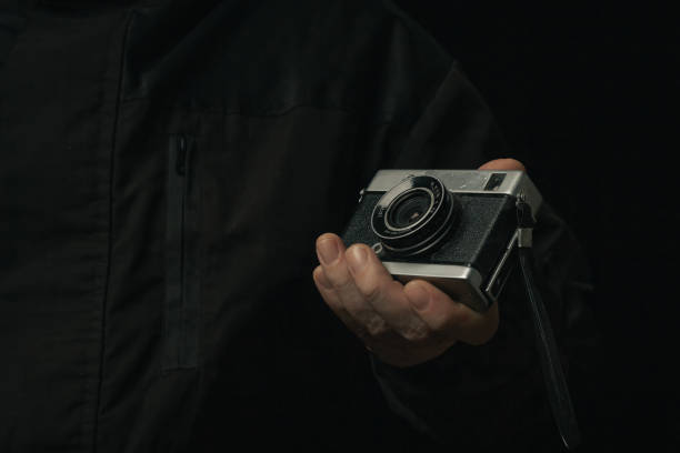 istock man holding Retro film photo camera isolated on black background soviet 1444921536