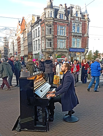 A young  street musician  gives a real piano performance on Muntplein in the city of Amsterdam.