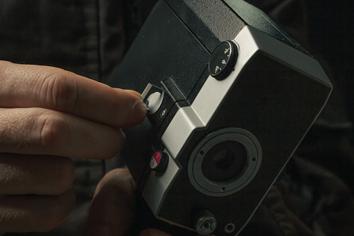 Vintage movie camera in man hand isolated on a blackbackground