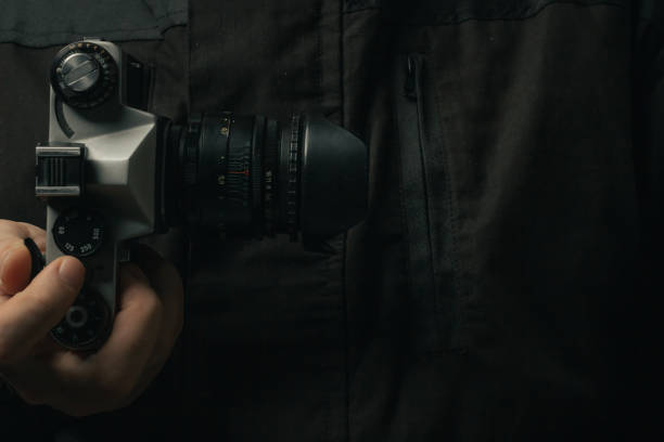 istock man holding Retro film photo camera isolated on black background soviet 1444927621