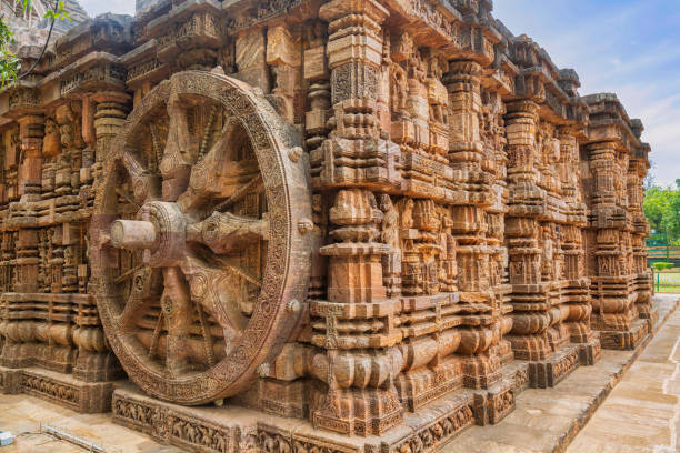 Stone wheel and ancient carving on the wall of Konark Sun Temple at Puri, Odisha, India. Ancient stone carvings with large stone wheel of a chariot on the wall of Konark Sun Temple at Puri, Odisha, India. chariot wheel at konark sun temple india stock pictures, royalty-free photos & images